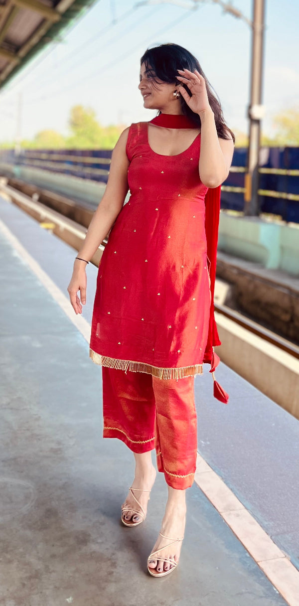 Woman in a red traditional outfit standing on a platform with a train in the background